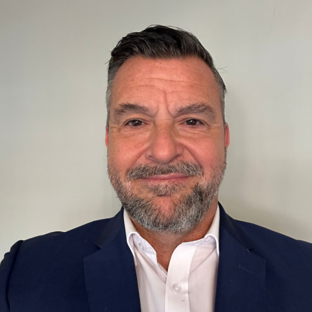 Mark Mullin A smiling man in a suit, with a neat beard, against a plain background.